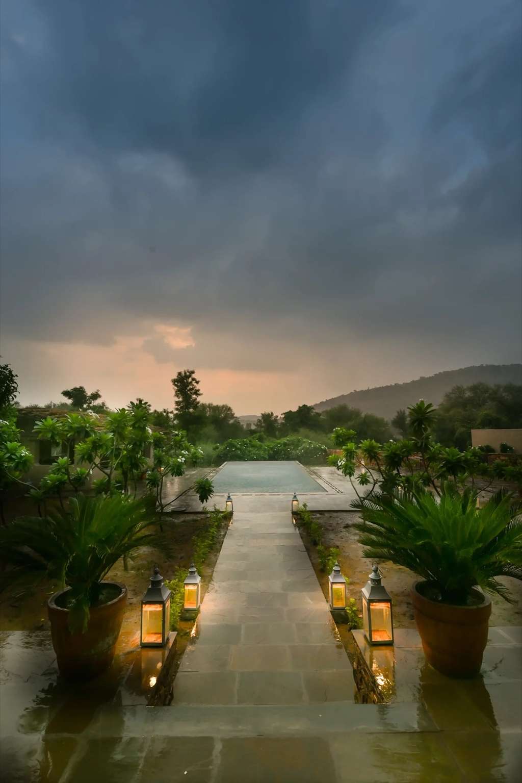 Lantern-lit pool and stone walkway at dusk