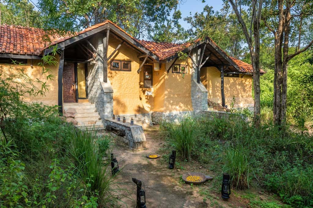A bungalow at Kanha Earth Lodge, mud plaster and tiled roof among the trees