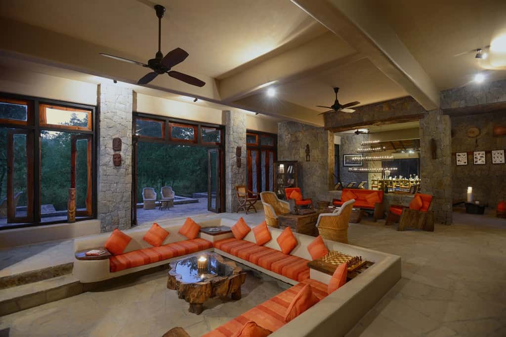 The lounge at Kanha Earth Lodge, sunken seating around a tree-trunk table