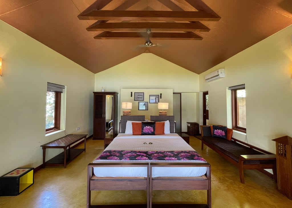 Chakra Cottage bedroom with gabled ceiling, wooden beams and lotus-print bed runner at Anantya by the Lake, Chittar