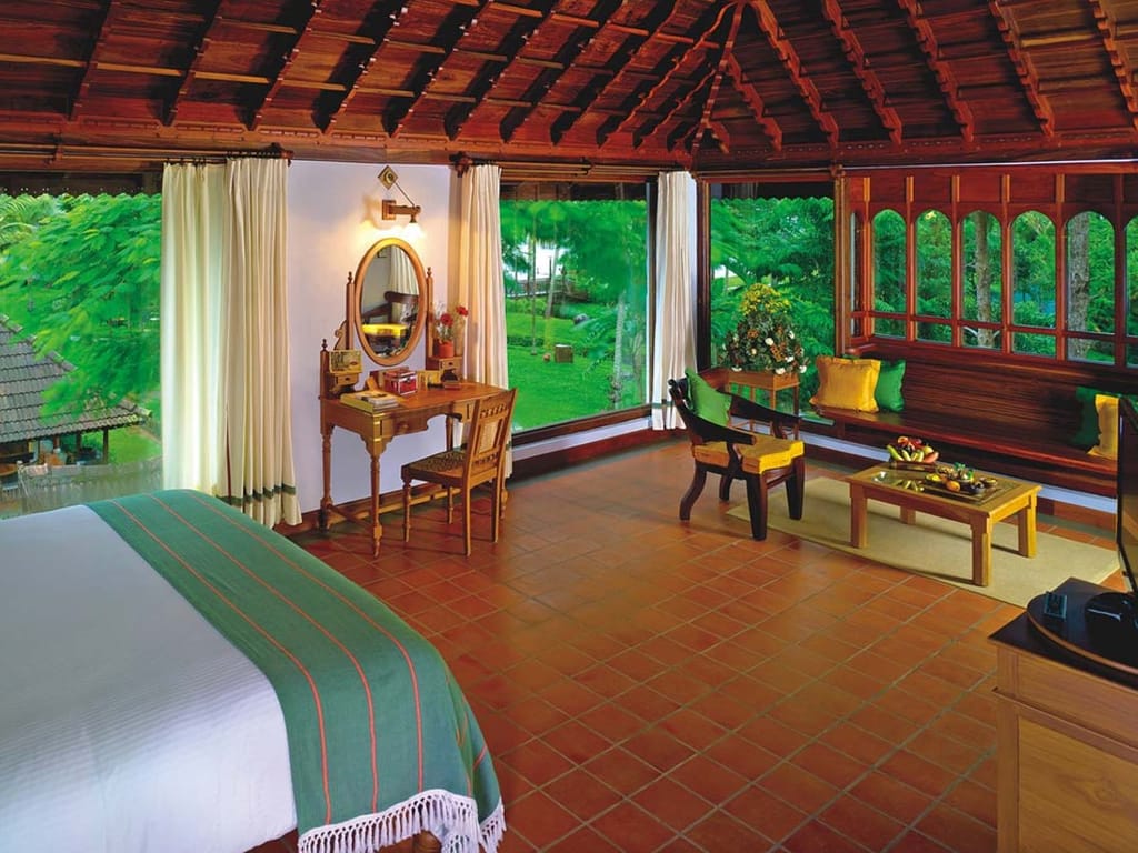 Luxury Pavilion Room with timber ceiling, terracotta floor, dressing table and picture windows onto gardens, Kumarakom Lake Resort, Kumarakom