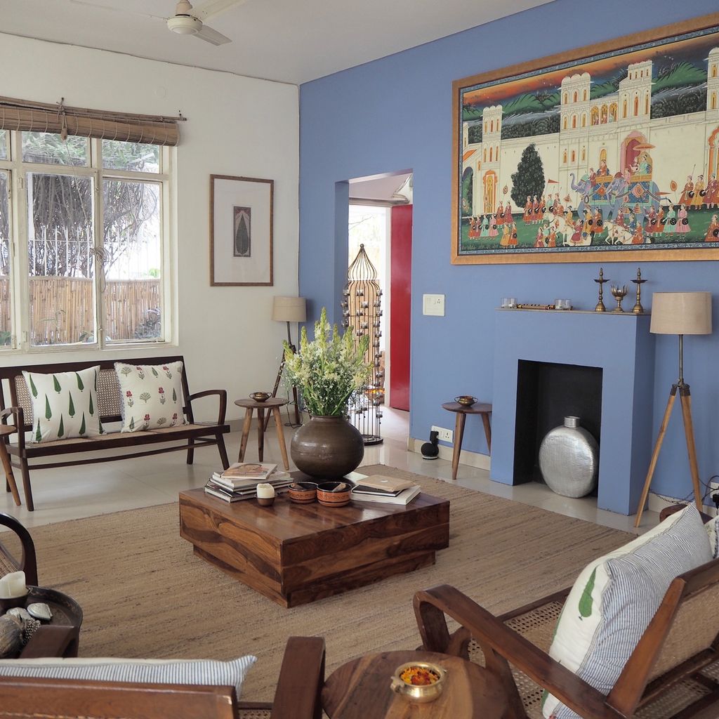 Main lounge with a blue fireplace wall, framed Indian painting and wooden furniture, Mizpah Delhi, Delhi