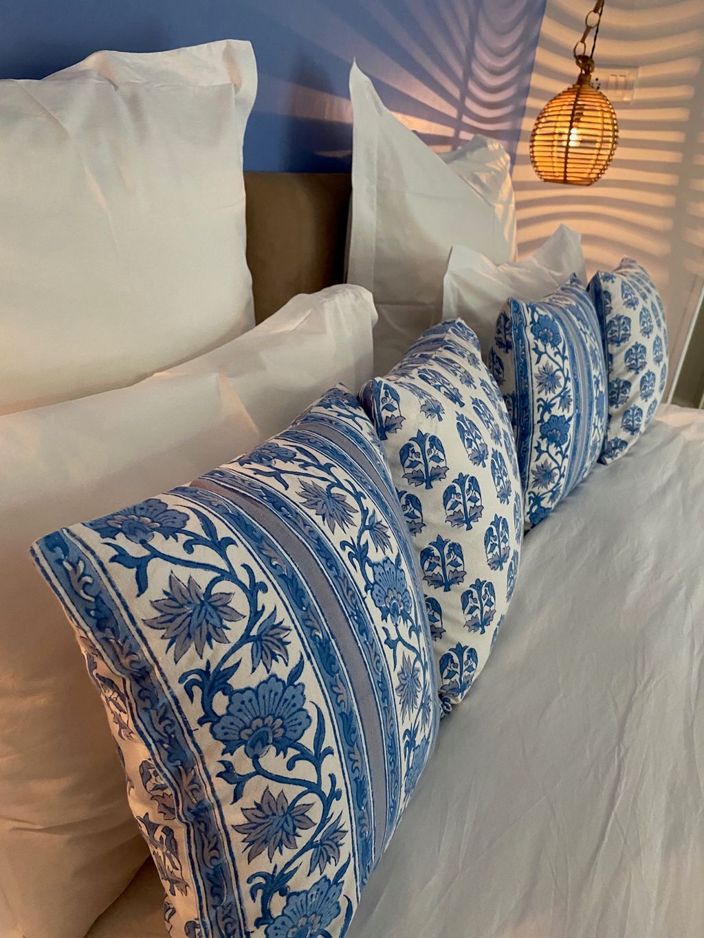 Blue block-print cushions and a cane pendant lamp in a guest bedroom, Mizpah Delhi, Delhi