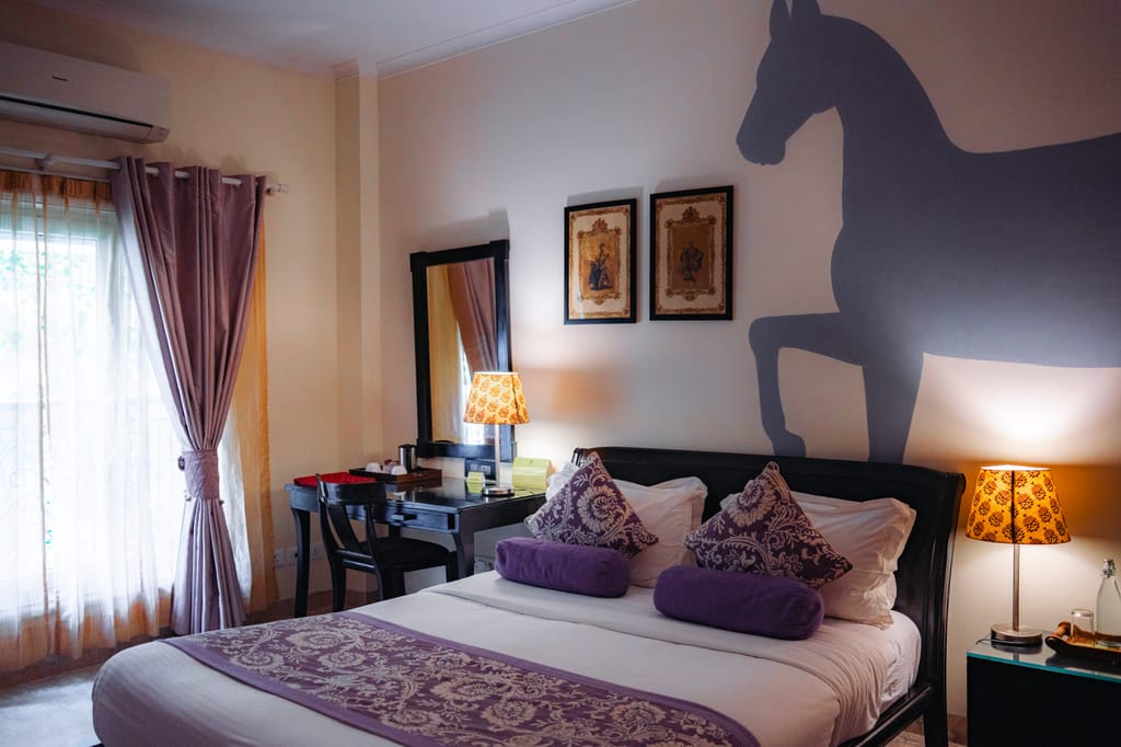Standard Room double with horse mural, purple textiles and writing desk, Colonel's Retreat, Delhi