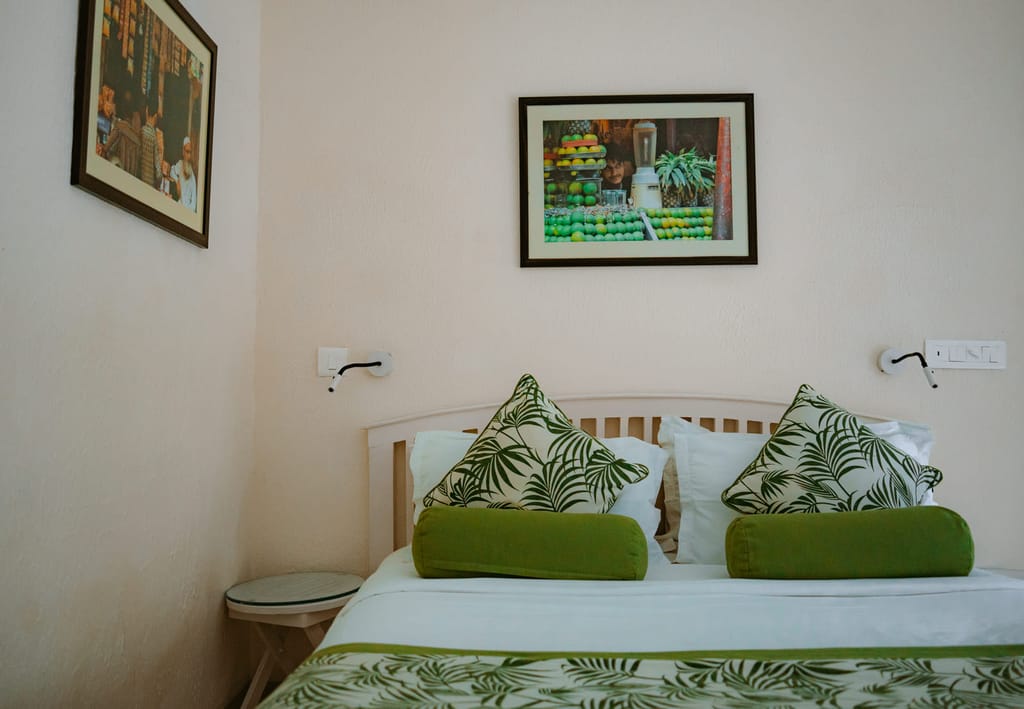 Standard Room double with palm-print cushions and framed photographs, Colonel's Retreat, Delhi
