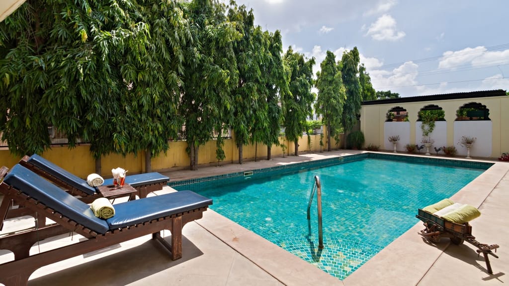 Outdoor swimming pool with wooden loungers, Dera Rawatsar, Jaipur