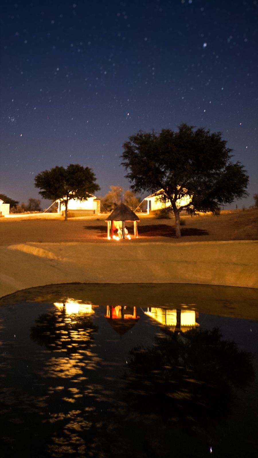 Campfire and tents reflected in the pond at night, Dhora Desert Resort & Spa, Shekhala