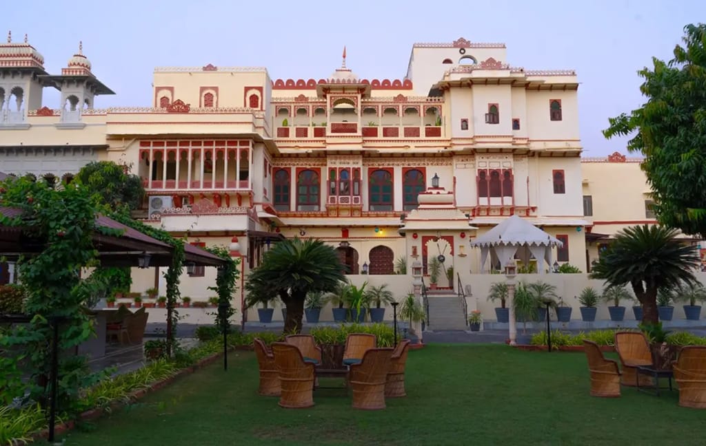 Cream-and-red fort facade with carved balconies and garden lawn at dusk, Fort Dhariyawad, Dhariyawad