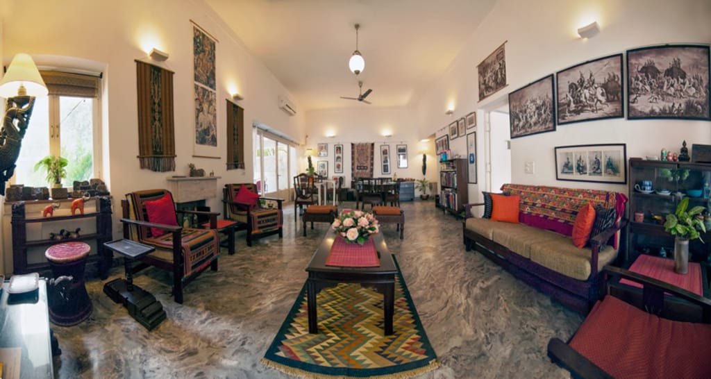 Living room with carved wood furniture, durries and the hosts' photography on the walls, Haveli Hauz Khas, New Delhi