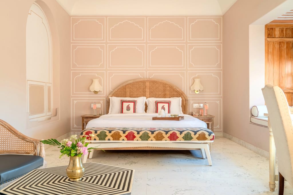 Bedroom with white Jaipur-style wall motifs and a kilim-upholstered bench, Niravi, Jaipur
