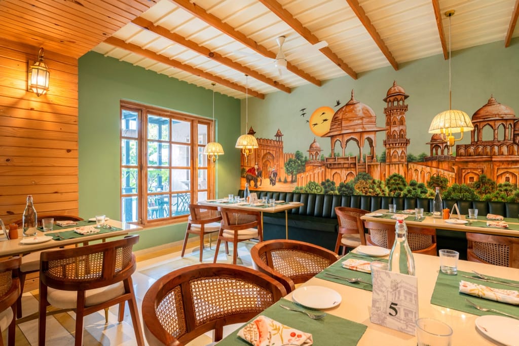 Restaurant interior with hand-painted Jaipur mural and cane-backed chairs, Niravi, Jaipur