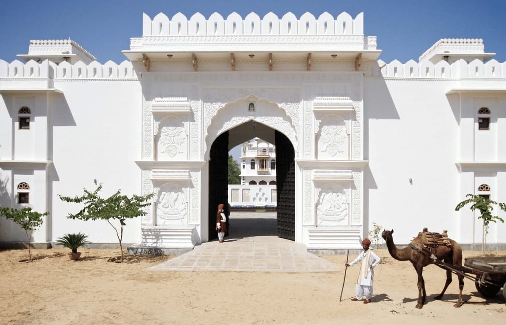 Carved white entrance gate with doorman and camel cart outside the walls, Talabgaon Castle, Talabgaon
