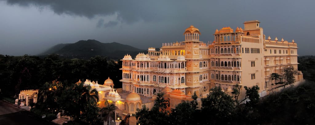 Chunda Palace exterior lit at dusk against the Aravali hills
