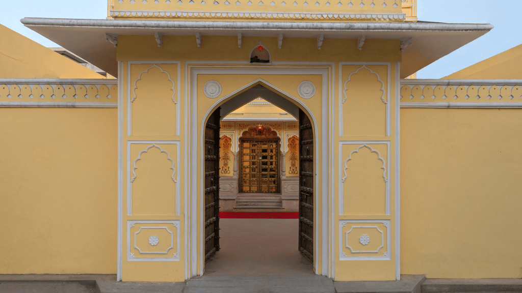 Arched entrance gate of the yellow castle facade, lit in the evening