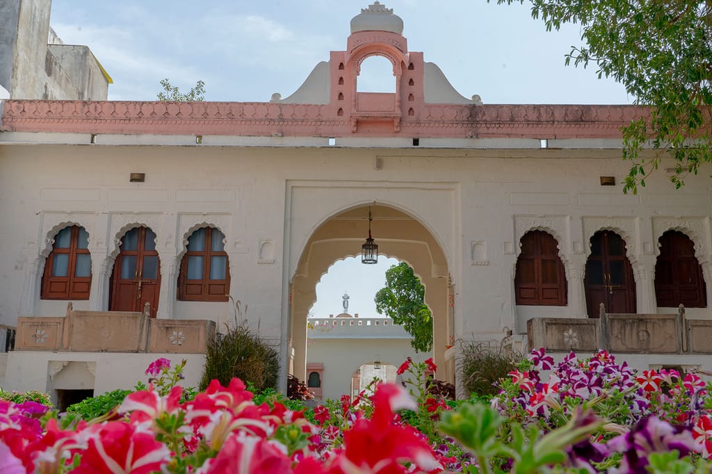 Fort facade with arched gateway seen over flowering shrubs