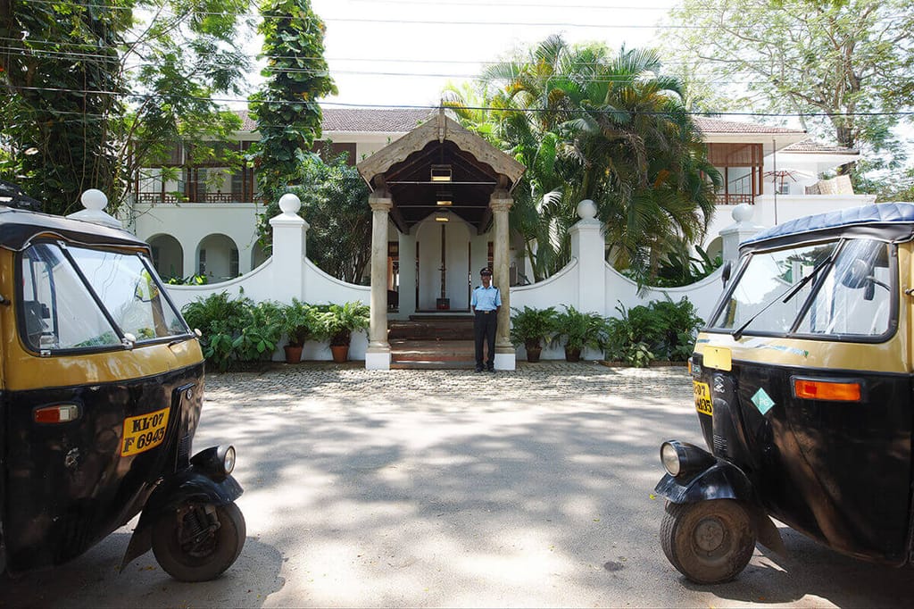 Entrance gate of The Malabar House with auto-rickshaws waiting outside on Parade Road, Fort Cochin