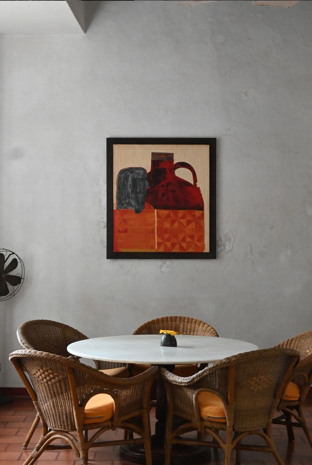 Dining corner at Old Harbour Hotel: cane chairs around a round marble-topped table below a framed artwork