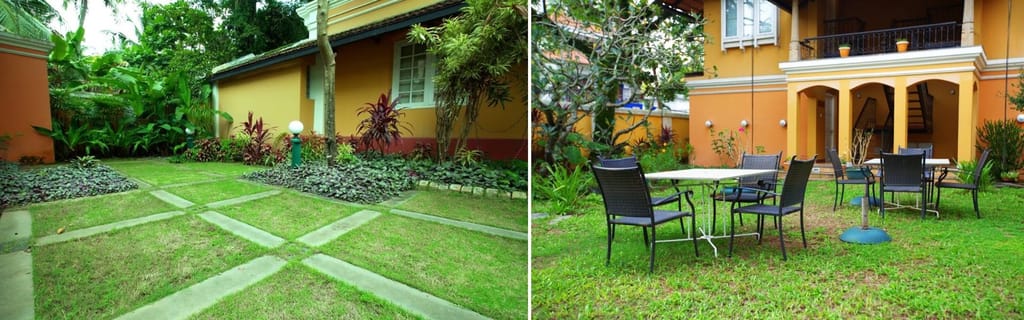Tea Bungalow, Fort Kochi: the garden lawn with paved paths and iron tables and chairs under the palms in front of the house