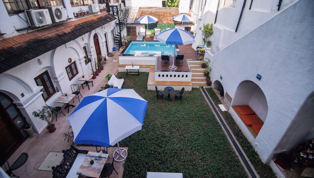 The Old Courtyard Hotel courtyard seen from an upper floor: lawn, blue and white umbrellas, pool and timber deck