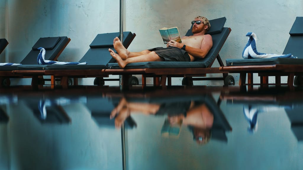 Guest reading on a lounger beside the swimming pool