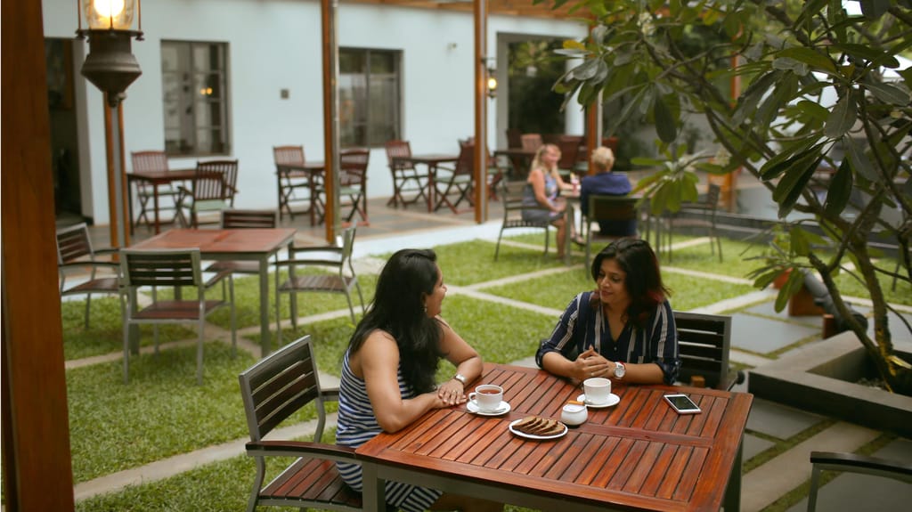 Garden courtyard dining at the East Indies restaurant, tables on grass squares under a frangipani tree