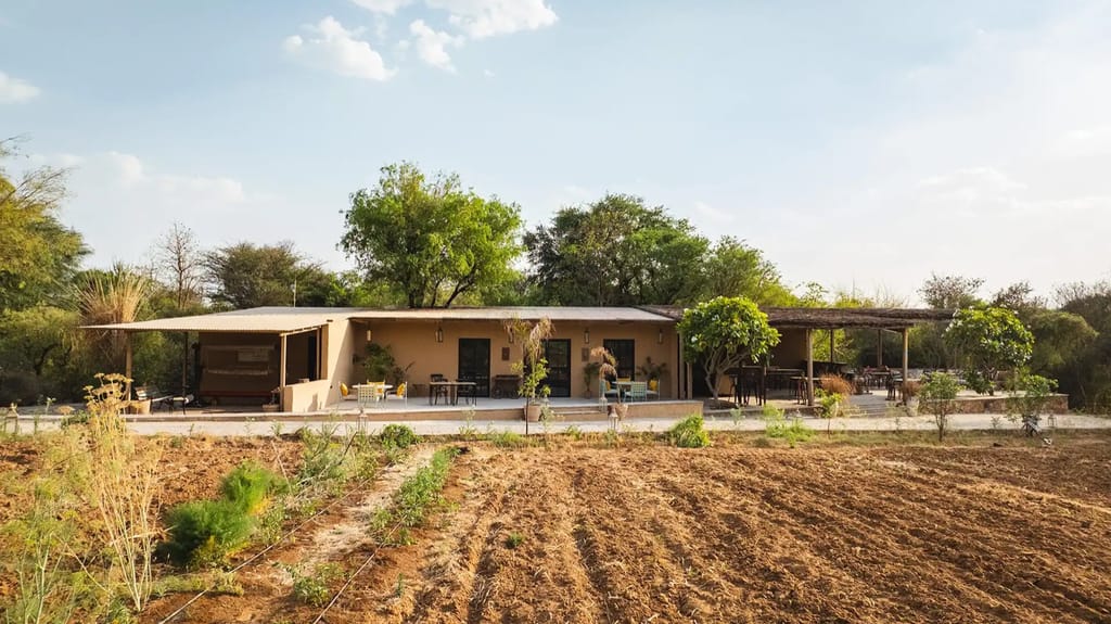Low villa building across a ploughed farm field