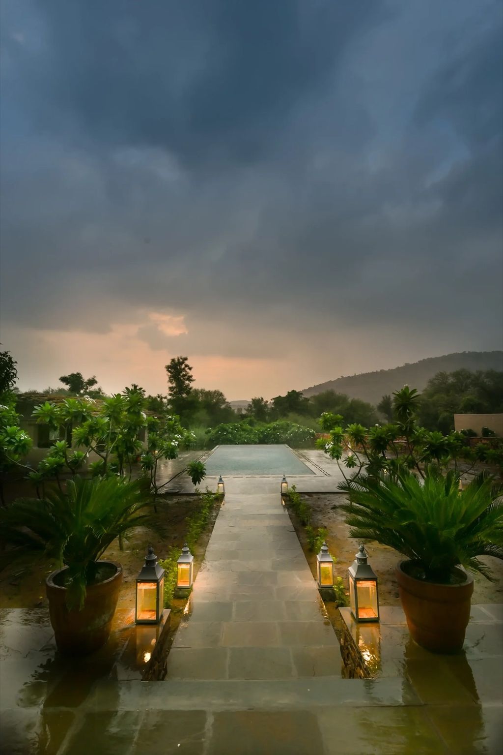 Lantern-lit pool and stone walkway at dusk