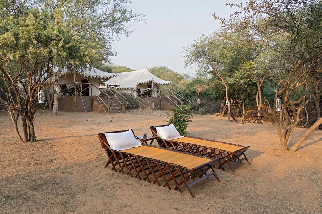 Wooden daybeds outside the canvas tents