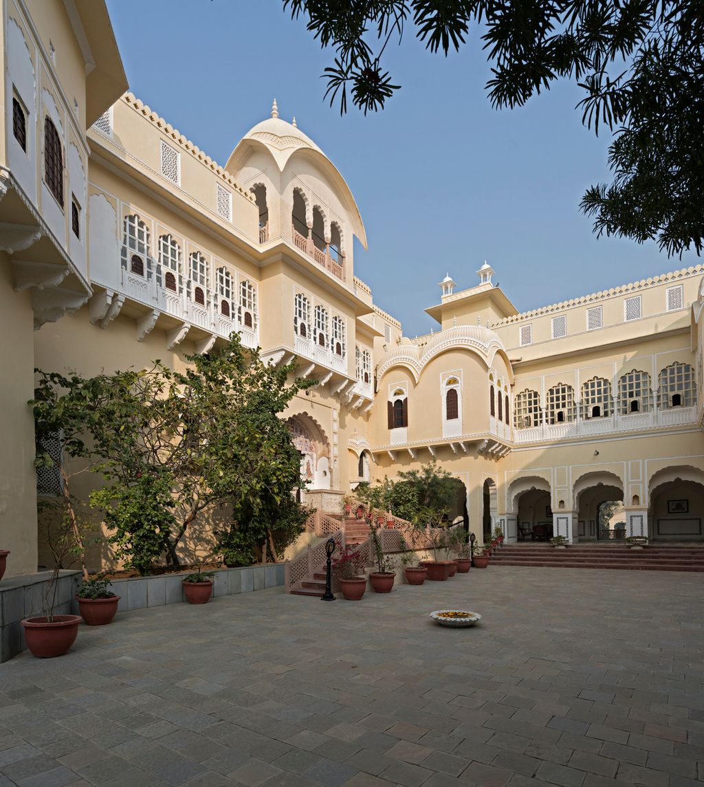 Inner courtyard with white jharokha balconies and a domed pavilion above the steps