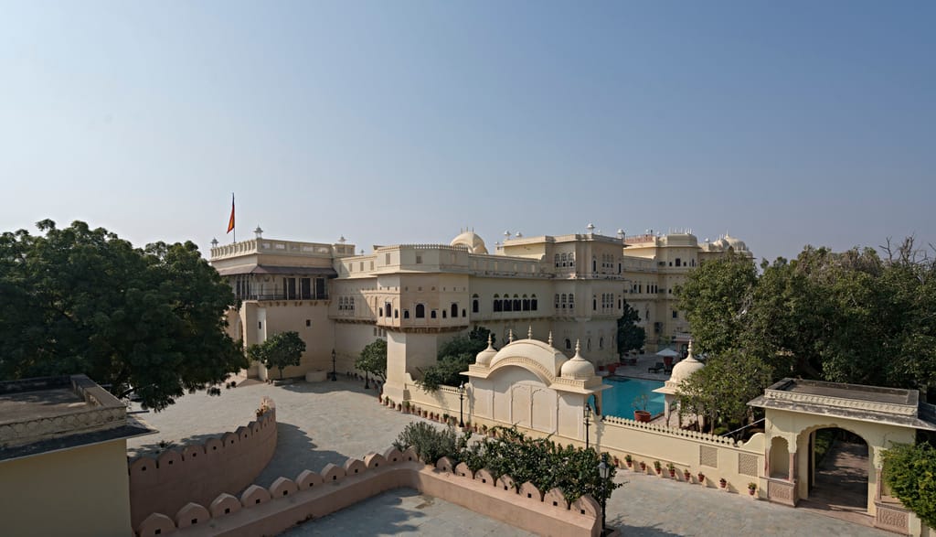 The palace seen from the outer wall, chhatris along the roofline and the pool at the side