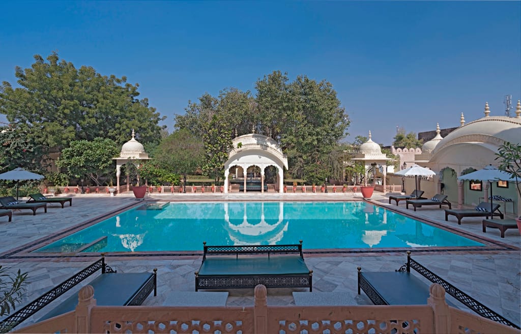 Swimming pool with domed gazebos and loungers along the paved surround