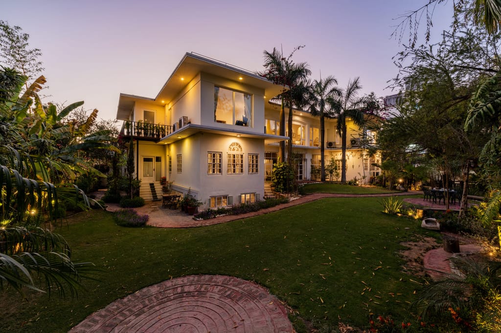 Villa lit at dusk above the lawn