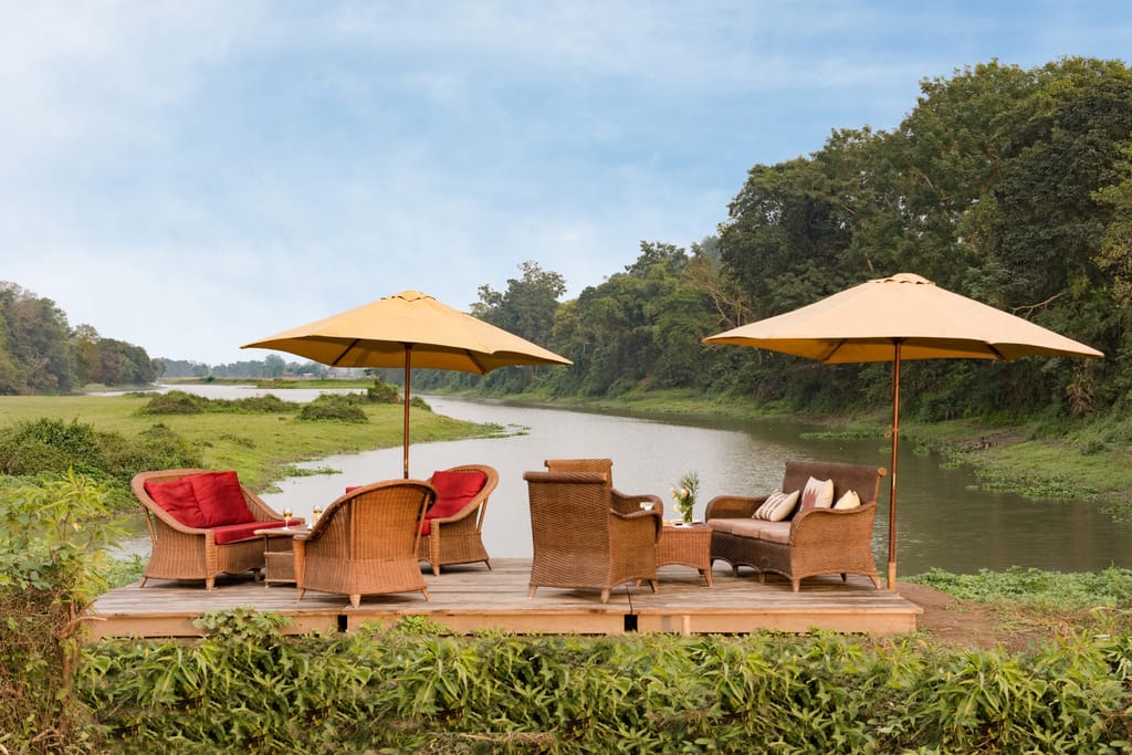 Wicker chairs and umbrellas on the riverside deck above the Diphlu river