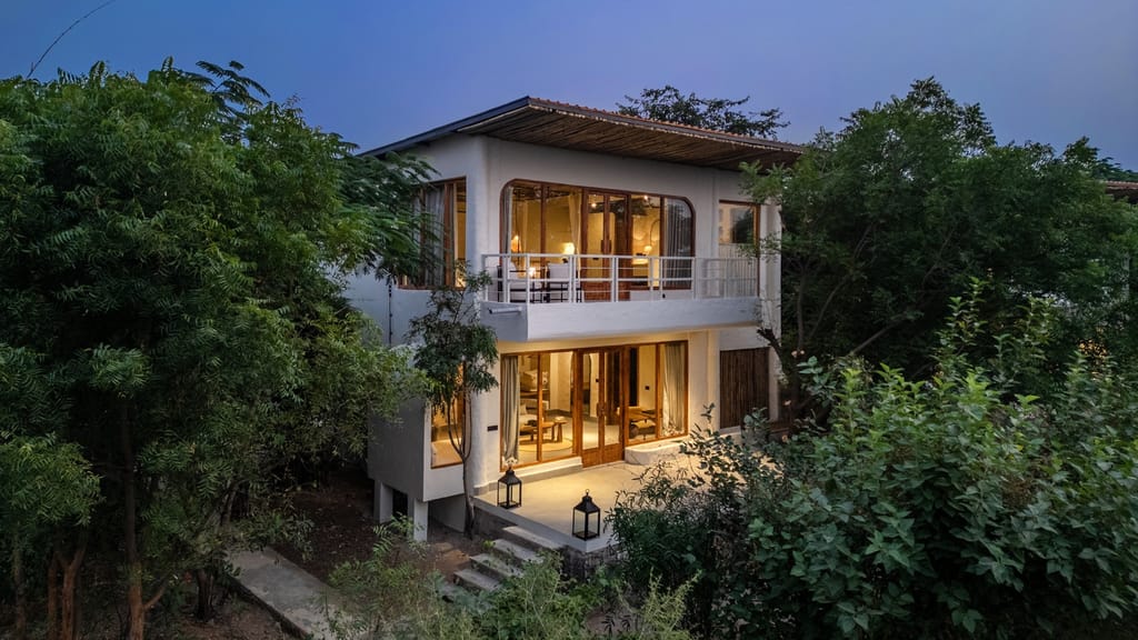 Two storey Forest Villa lit at dusk among trees