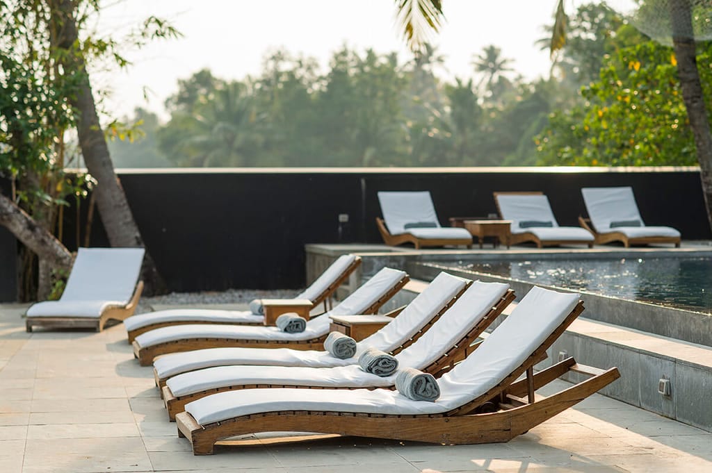 Teak loungers beside the black edged swimming pool