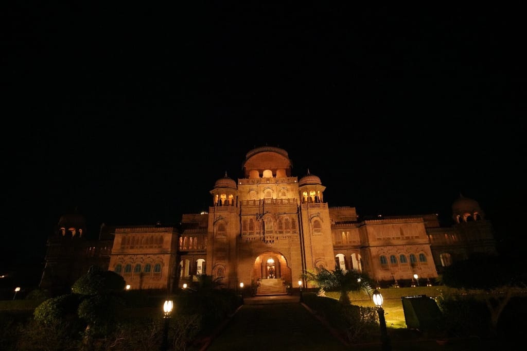Palace floodlit at night with lamps along the garden path