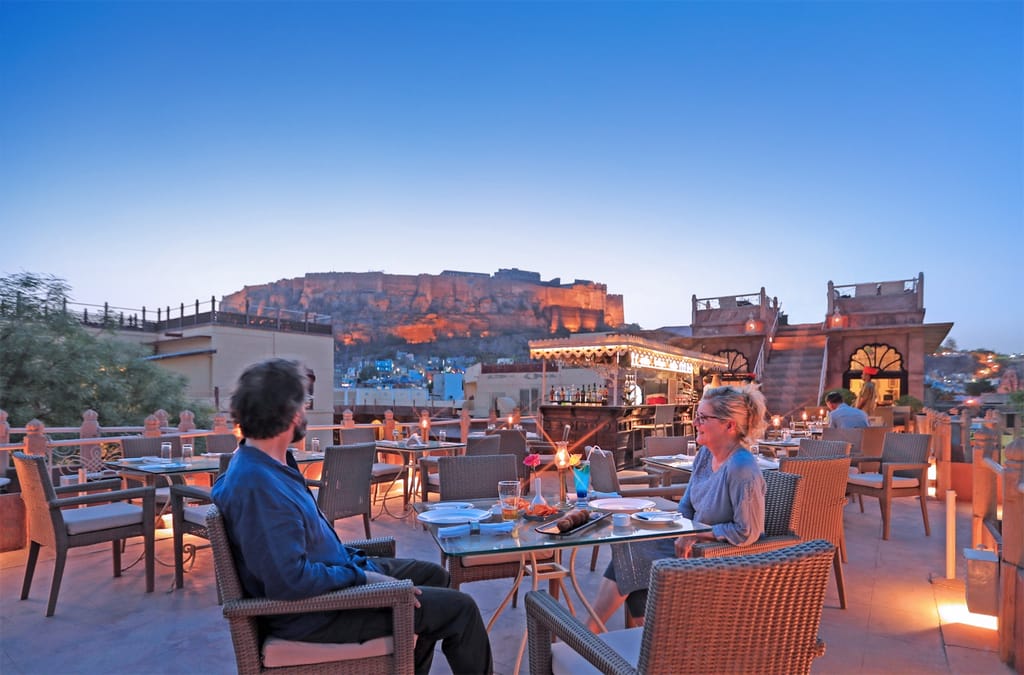 Rooftop restaurant tables facing Mehrangarh fort at dusk