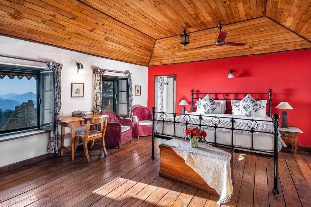 Red-walled suite with iron bed and wooden floor