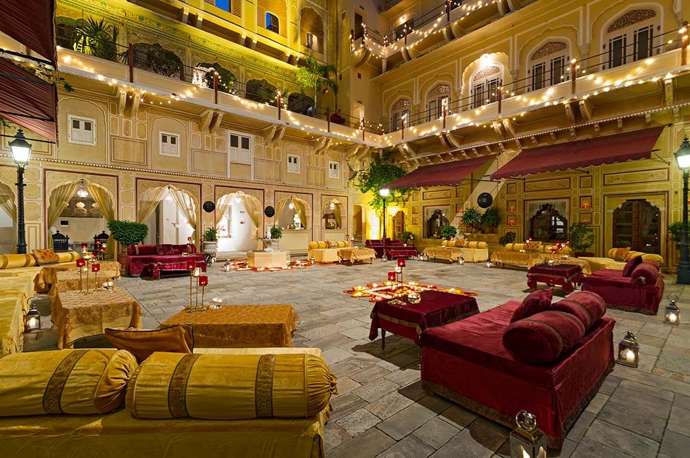Painted durbar hall with red divans lit at night