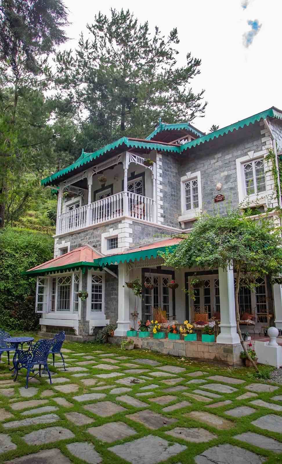 The villa from the garden path with blue chairs on the grass