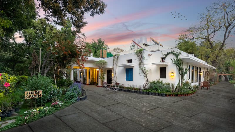 The white 1937 bungalow at dusk, with its garden, herb beds and blue shutters, Lutyens Bungalow, New Delhi
