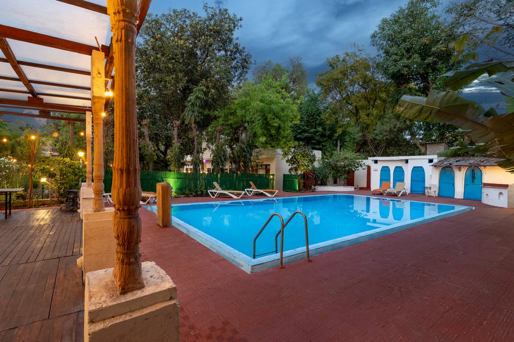 The swimming pool in the garden at dusk, seen from the carved-pillar veranda, Lutyens Bungalow, New Delhi