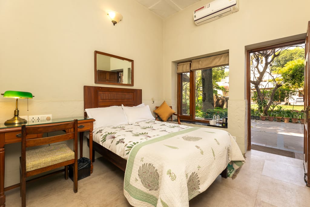 A double room with its own door onto the garden, desk and green-shaded lamp, Lutyens Bungalow, New Delhi