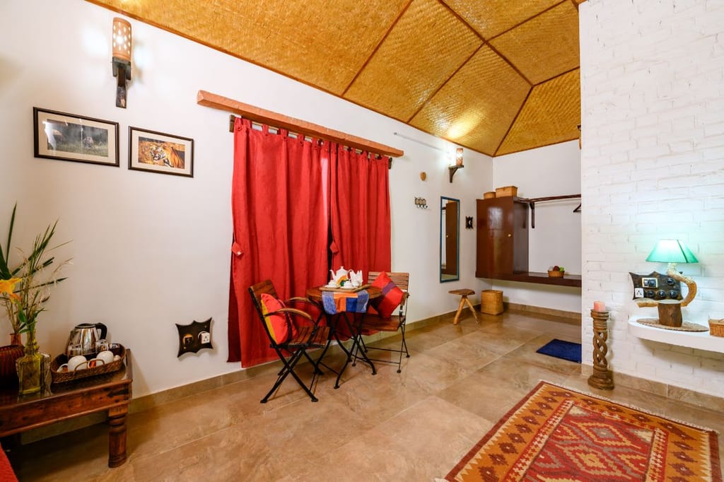 A cottage bedroom with red curtains and a table by the window