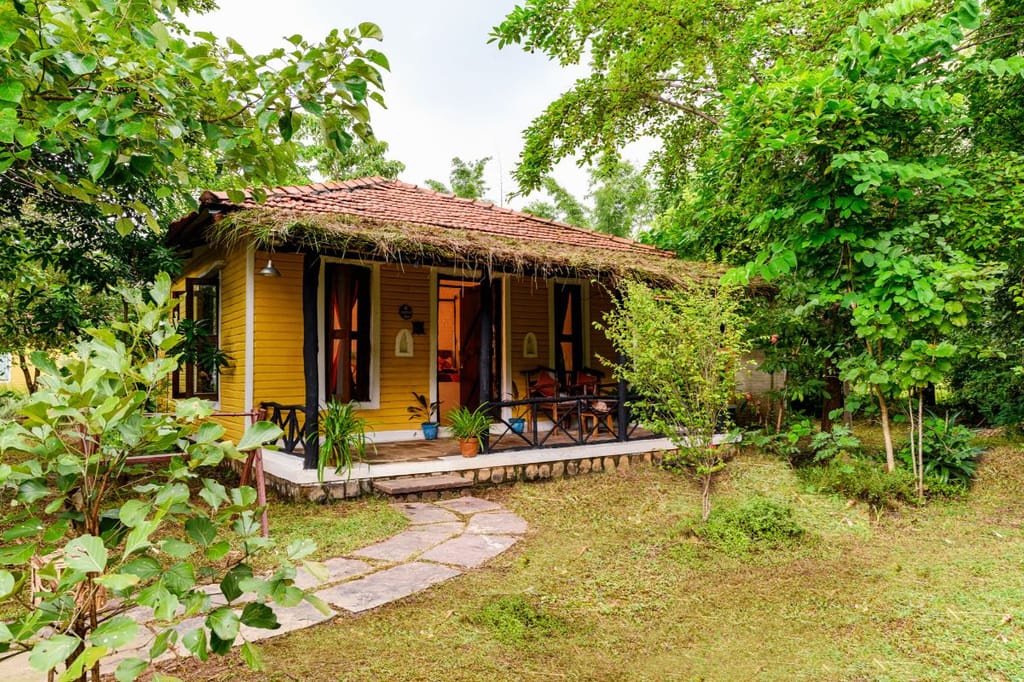 A yellow timber cottage with a tiled roof and its own verandah