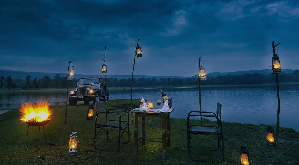 Dinner laid by the water at dusk, lit by lanterns