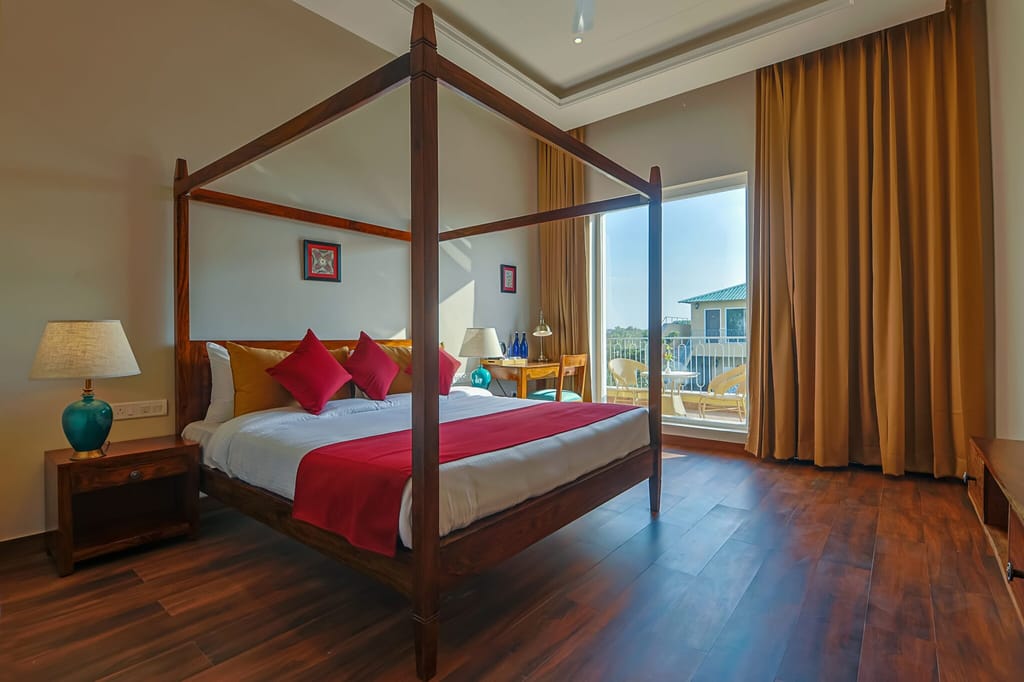 A four-poster bed and wooden floor in a room at Ananyamaya
