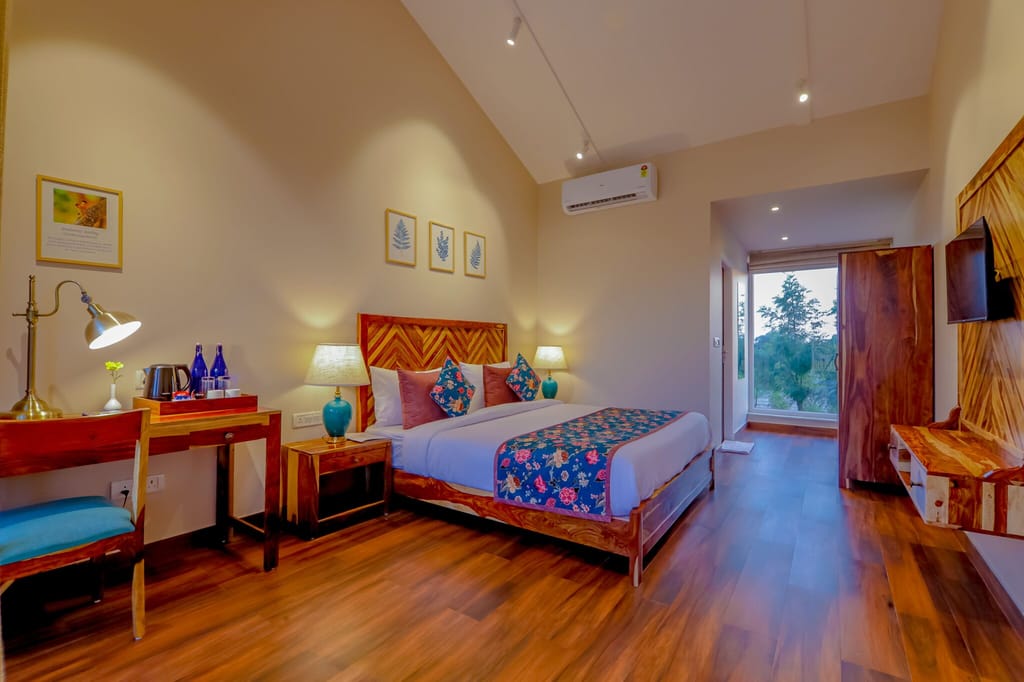 A garden-facing room at Ananyamaya with a desk and balcony