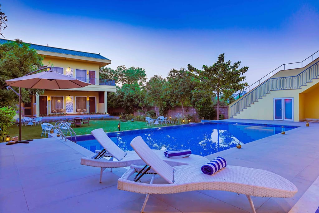 The pool and garden at Ananyamaya, sun loungers under a parasol