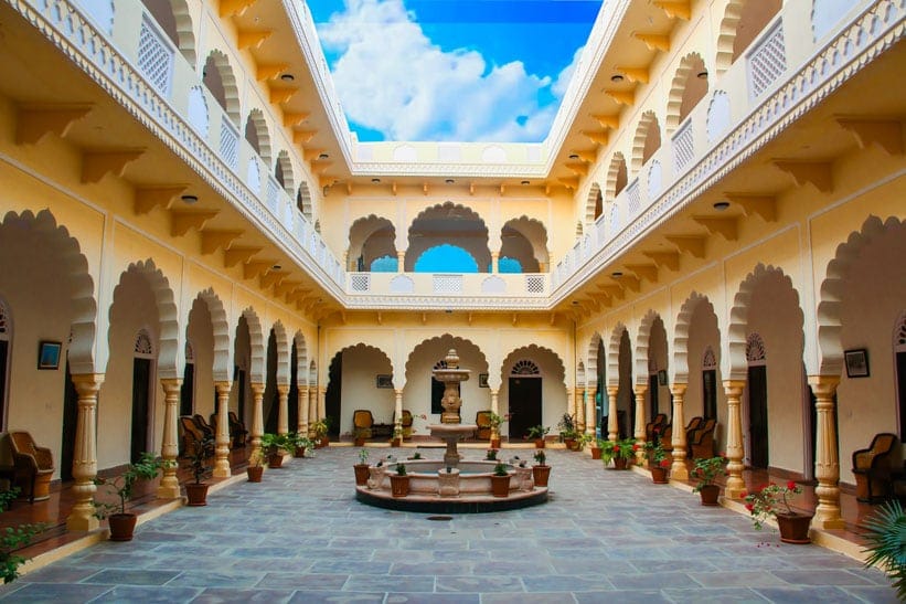 The open courtyard of the haveli, scalloped arches around a fountain
